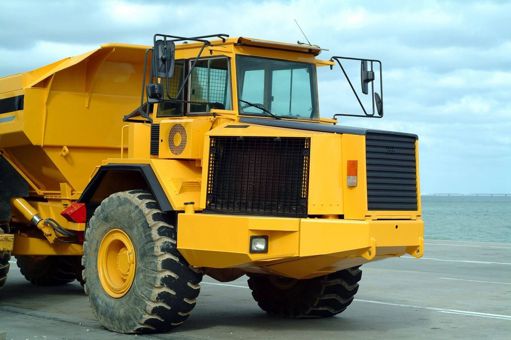 A yellow dump truck is parked on the side of the road.