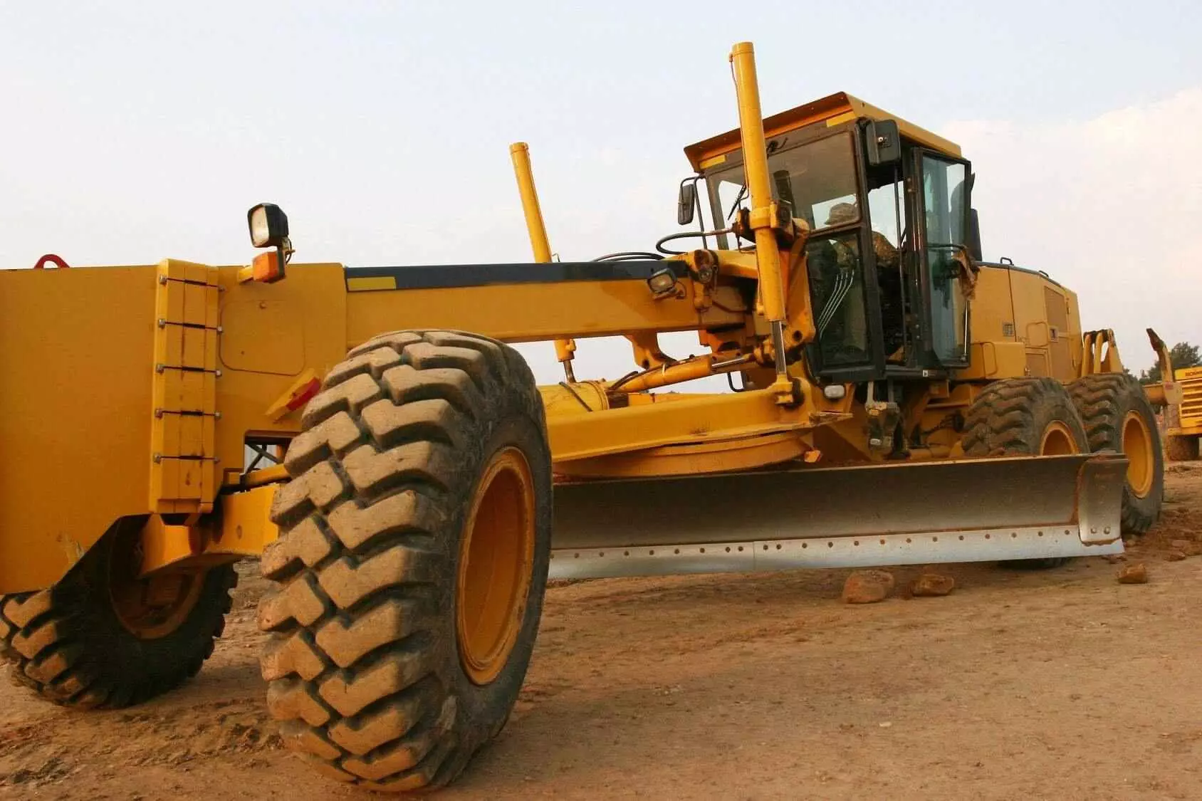 A yellow tractor with large tires is parked on the dirt.