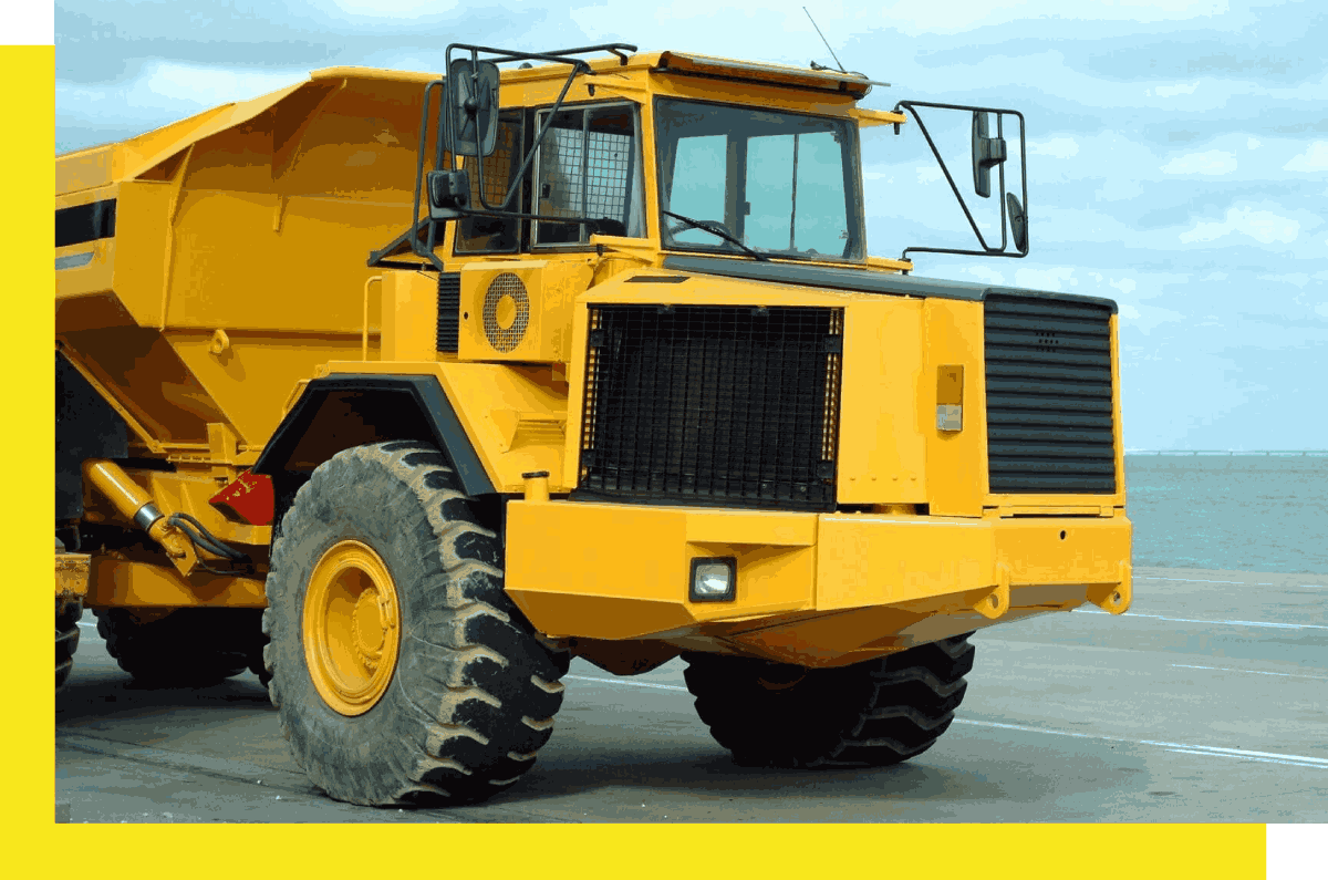 A yellow dump truck parked on the side of a road.