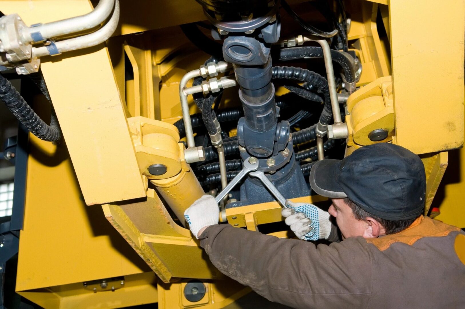 A man working on the underside of an engine.